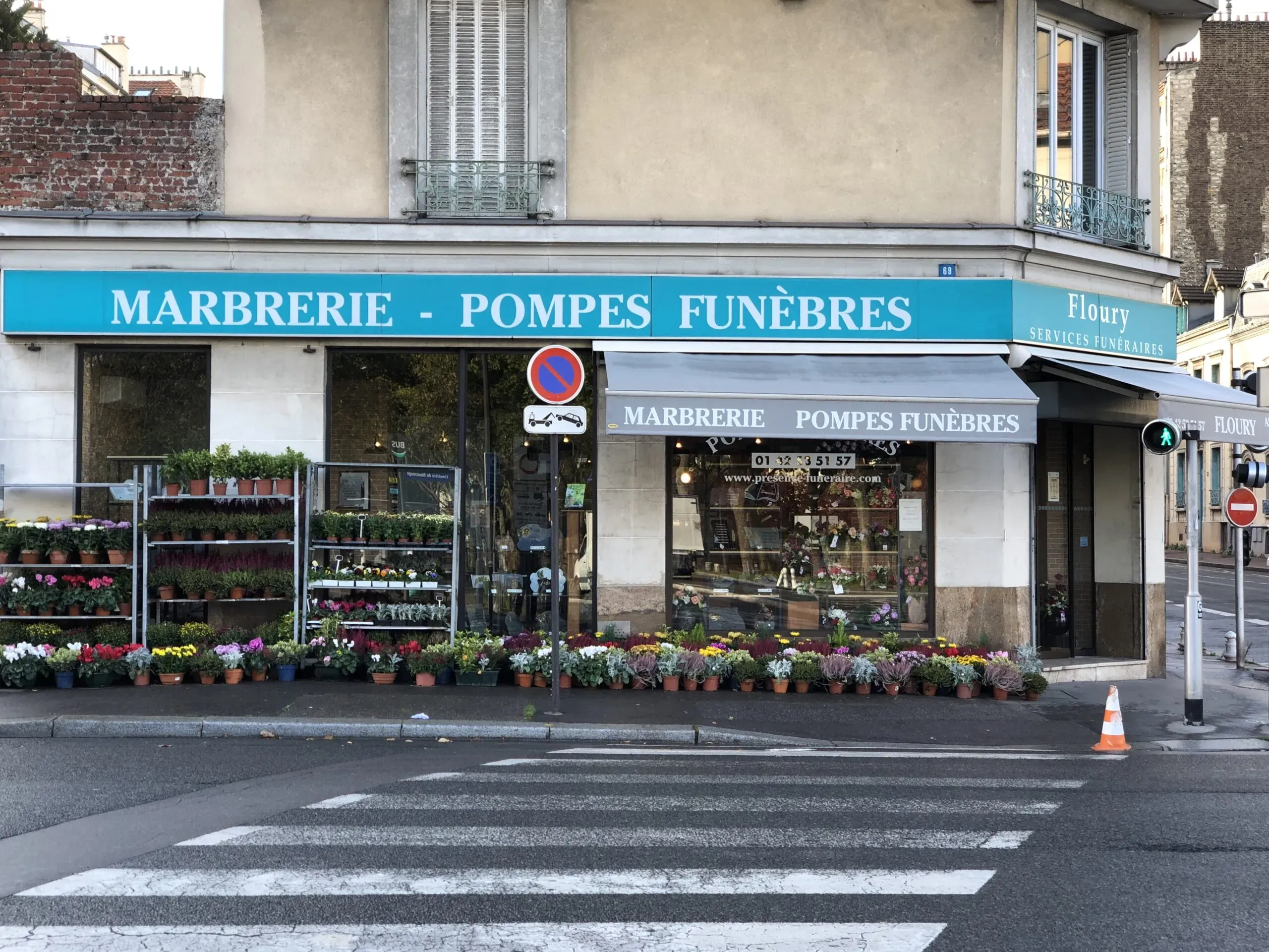 Façade de l'agence de marbrerie et pompes funèbres Floury avec des fleurs exposées à l'extérieur.