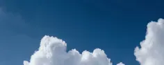 Bannière illustrant un ciel d'un bleu profond parsemé de nuages blancs vaporeux.